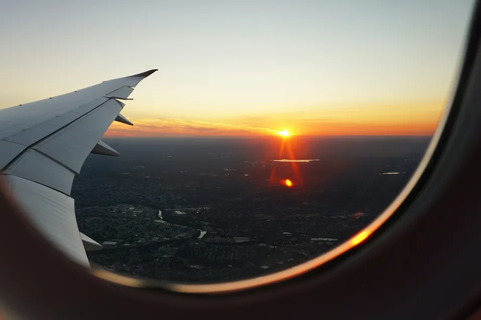 The sun setting over a city, seen through an airplane window