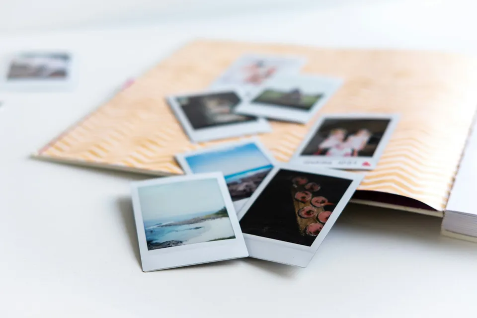 Instant photos scattered next to an open handmade photo book